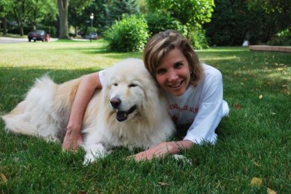 A photograph of Evanger's owner Holly Sher lovingly hugging her fluffy white dog Yukon