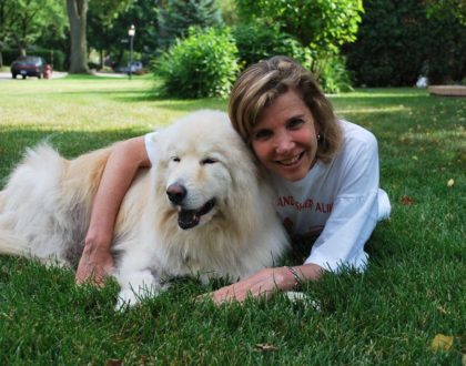 A photograph of Evanger's owner Holly Sher lovingly hugging her fluffy white dog Yukon